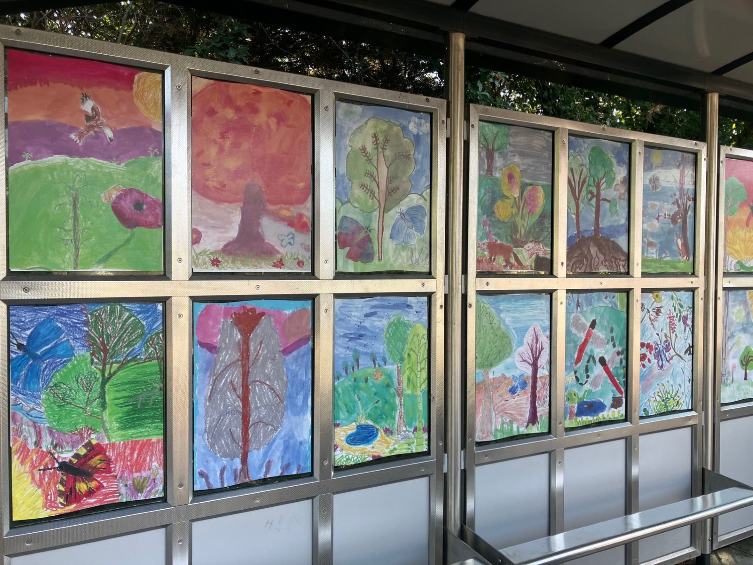 Two rows of children's nature paintings mounted in the station shelter panels